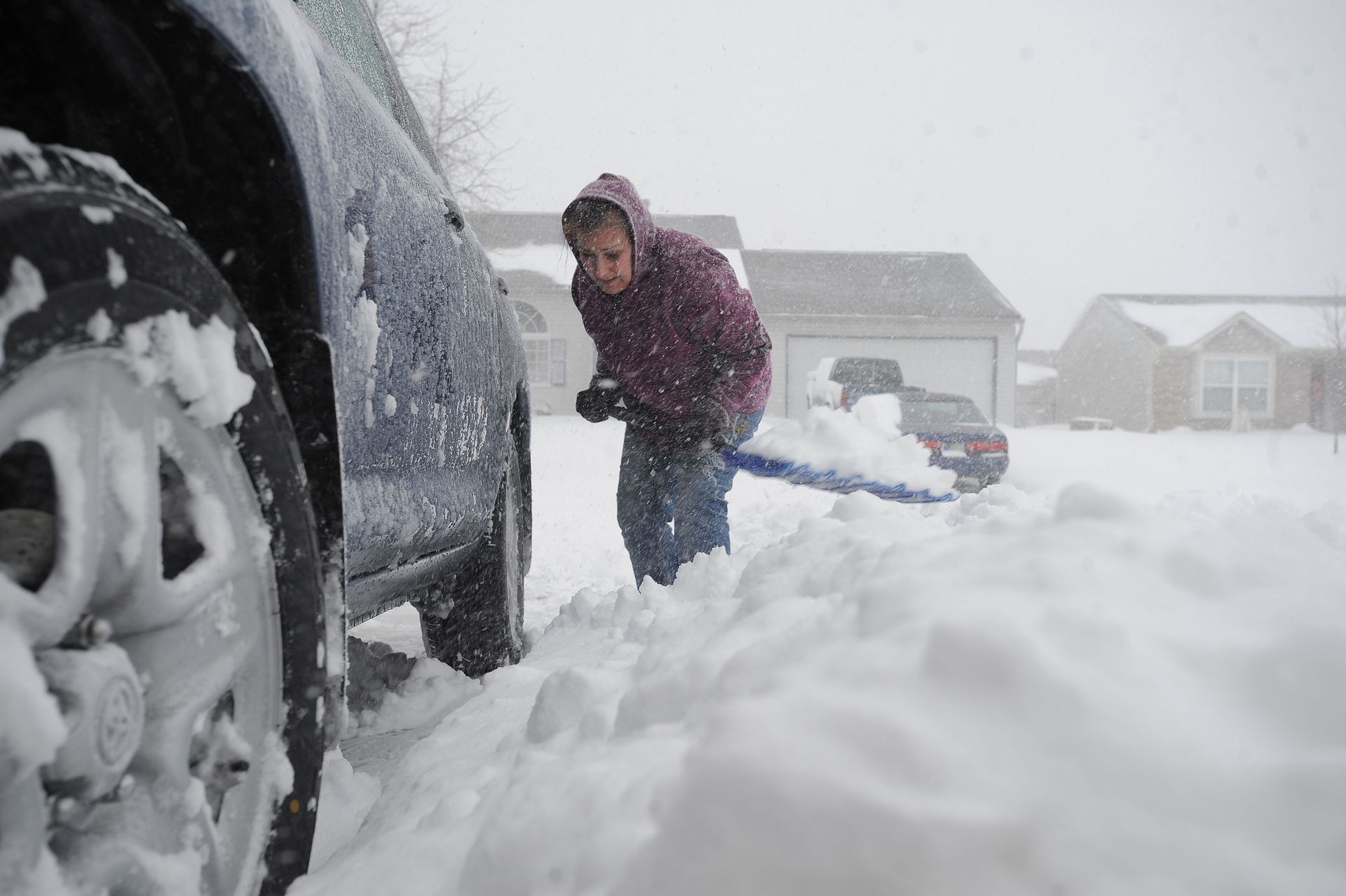 This is a current 2019 view a woman shoveling snow in her driveway in Franklin, Indiana, USA. This is a photo.